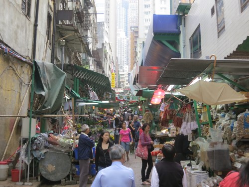 Various vendors and stalls selling their wares at a local street market as the ever-present skyscrapers loom ominousliy in the background