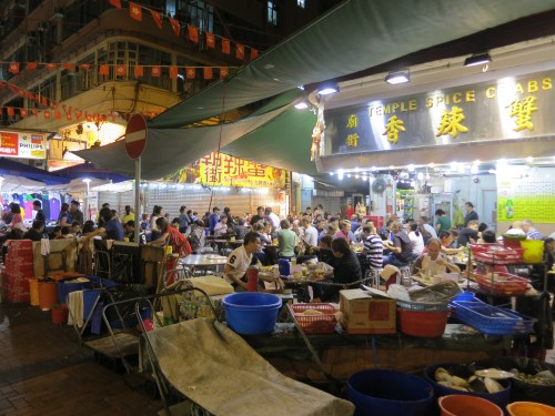 Diners enjoying the festive atmosphere and tasty treats near a street market in Kowloon