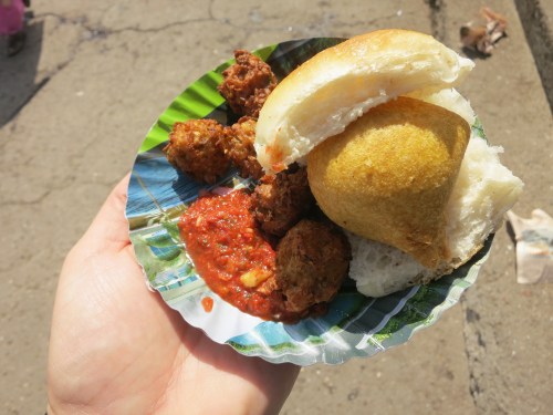 Vada Pau (sometime written Vada Pao) -- joking known as an "Indian Burger," this staple of Bombay street food features a small potato pattie sandwiched in a slider bun.  In this iteration, it is also served with a few fried treats and a generous splash of chile sauce